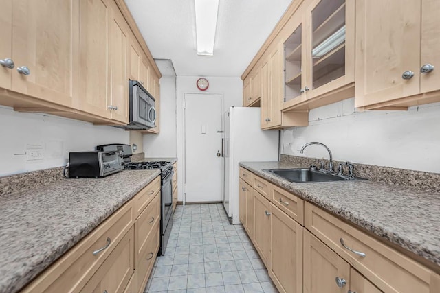 kitchen with light stone countertops, appliances with stainless steel finishes, light brown cabinetry, and sink