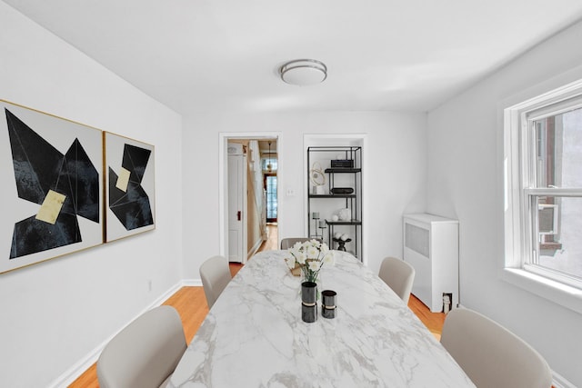 dining area with radiator heating unit, baseboards, light wood-style flooring, and a wealth of natural light