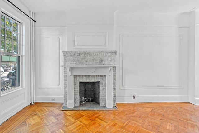 unfurnished living room with a brick fireplace, a decorative wall, and baseboards