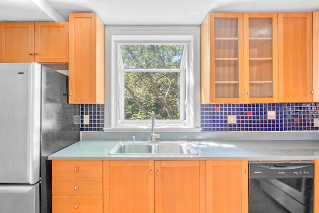 kitchen featuring dishwasher, glass insert cabinets, freestanding refrigerator, light countertops, and a sink