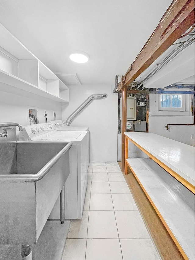 laundry area with laundry area, light tile patterned floors, electric panel, washer and dryer, and a sink