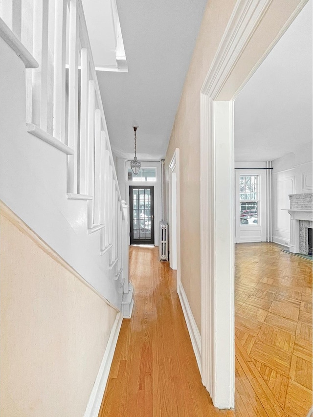 entrance foyer with radiator, stairway, a fireplace, and a healthy amount of sunlight