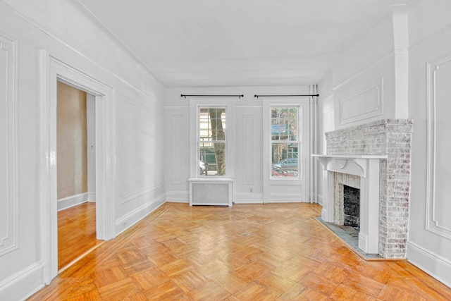 unfurnished living room featuring radiator heating unit, a fireplace, and a decorative wall