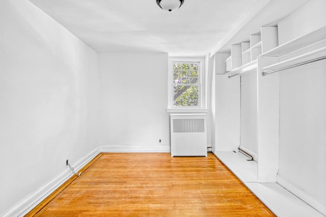 walk in closet with radiator and light wood-style floors