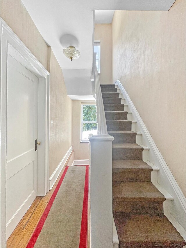 entrance foyer featuring radiator, plenty of natural light, a fireplace, and stairway