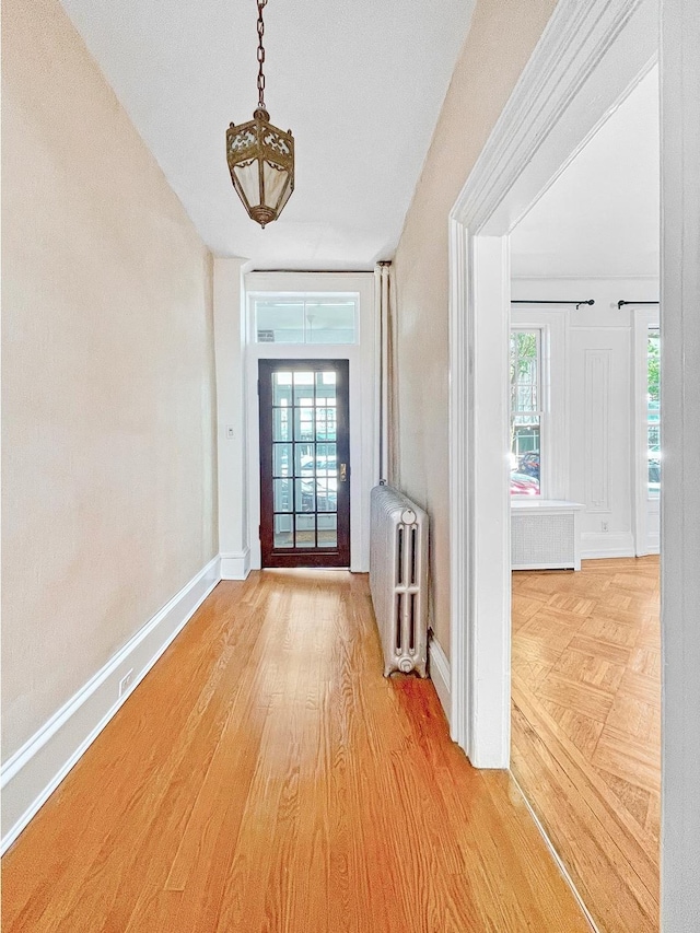 doorway featuring radiator, baseboards, and wood finished floors