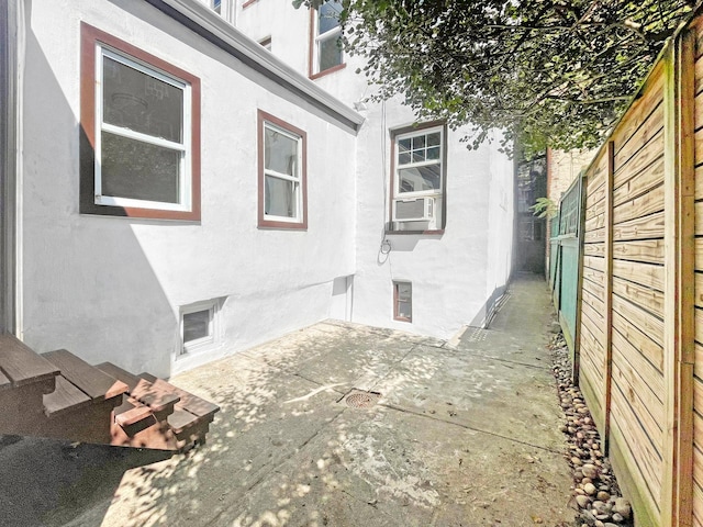 view of property exterior featuring cooling unit, a patio area, fence, and stucco siding