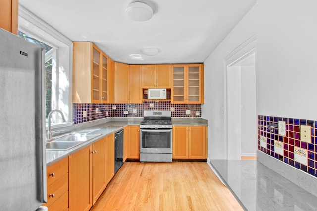 kitchen featuring glass insert cabinets, appliances with stainless steel finishes, light countertops, and a sink