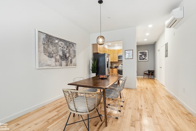 dining area with baseboards, an AC wall unit, and light wood-style floors