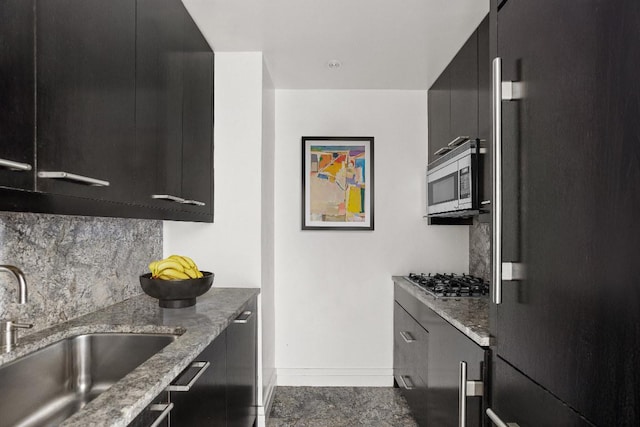 kitchen with light stone countertops, sink, backsplash, and appliances with stainless steel finishes