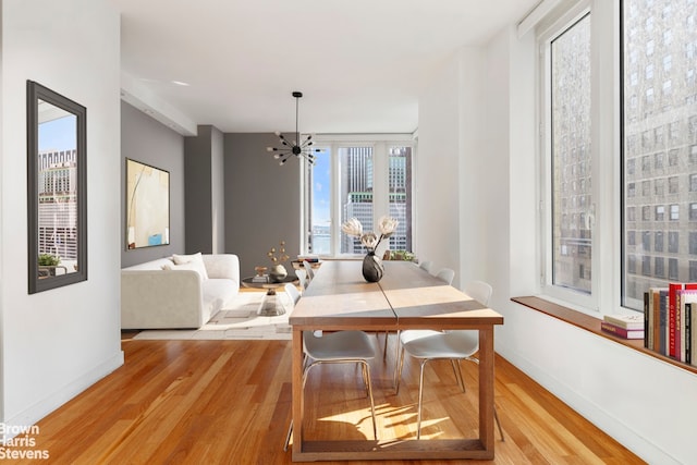 15 William St Unit 21A, New York City, NY 10004 - dining space featuring baseboards, a notable chandelier, and light wood-style floors