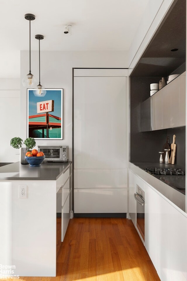 15 William St Unit 21A, New York City, NY 10004 - kitchen with wood finished floors, a toaster, stainless steel oven, modern cabinets, and white cabinets