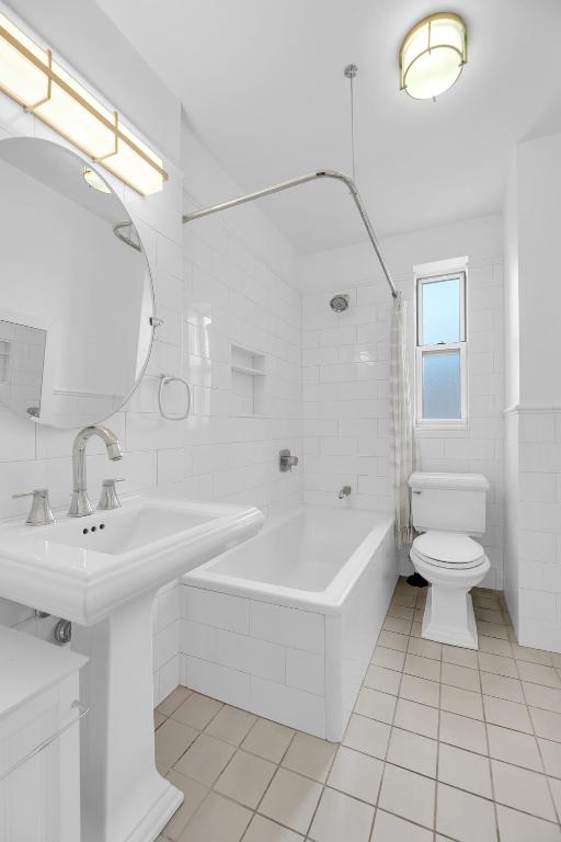 full bathroom with sink, tile walls, shower / bath combination with curtain, tile patterned flooring, and toilet