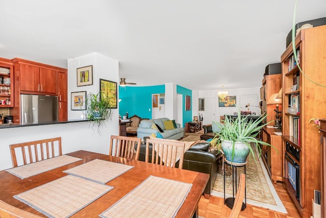 dining space featuring ceiling fan with notable chandelier