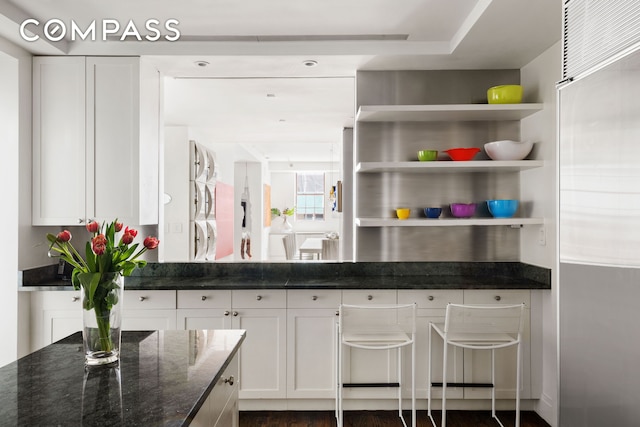 kitchen with dark stone countertops, open shelves, and white cabinetry