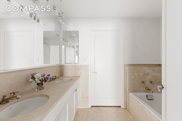 bathroom with tile patterned floors, tile walls, tiled tub, and a sink