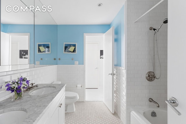 bathroom featuring  shower combination, double vanity, a sink, tile walls, and tile patterned floors