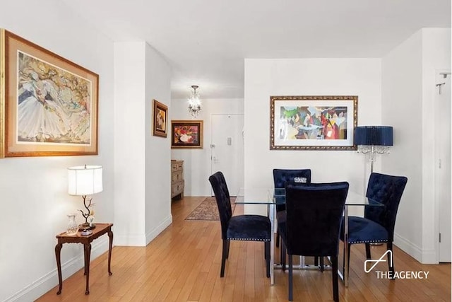 dining room with light wood-type flooring, an inviting chandelier, and baseboards