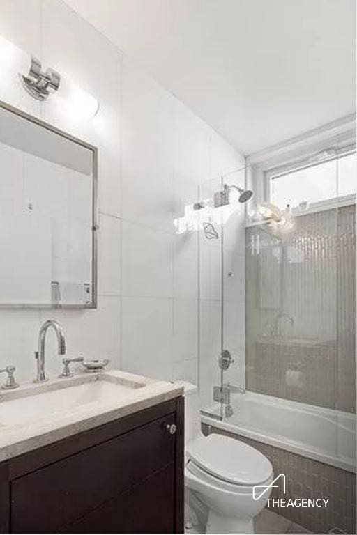 full bathroom featuring tiled shower / bath, vanity, and toilet