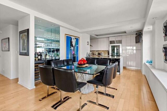 kitchen featuring white cabinetry, island exhaust hood, a raised ceiling, and light stone counters