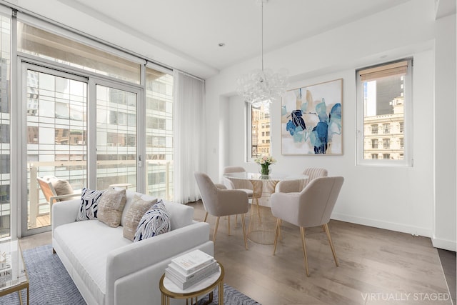 dining area featuring baseboards, a healthy amount of sunlight, an inviting chandelier, and wood finished floors