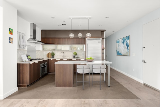 119 Fulton St Unit 10, New York City, NY 10038 - kitchen featuring wall chimney range hood, stainless steel appliances, light countertops, a center island, and decorative backsplash