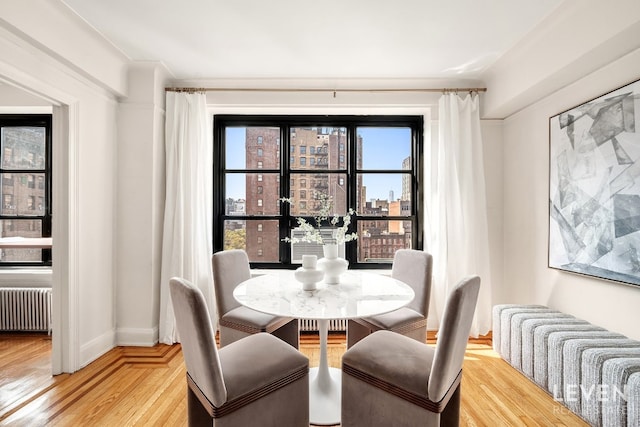 dining room with radiator heating unit, hardwood / wood-style floors, and plenty of natural light