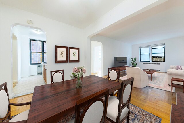 dining space featuring light parquet flooring, radiator, and cooling unit