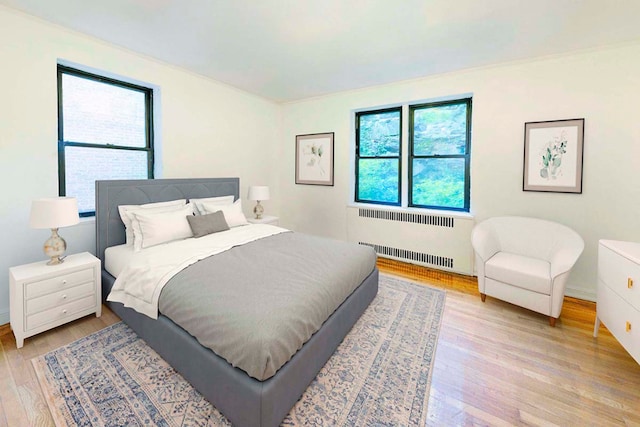 bedroom featuring radiator heating unit and light hardwood / wood-style floors