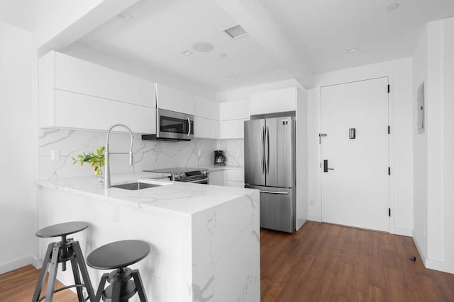 kitchen featuring a breakfast bar, sink, white cabinets, kitchen peninsula, and stainless steel appliances