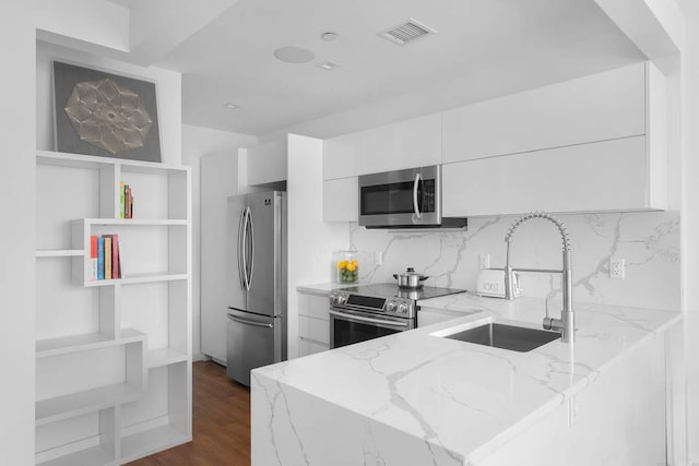 kitchen featuring dark hardwood / wood-style floors, white cabinetry, sink, stainless steel appliances, and light stone countertops