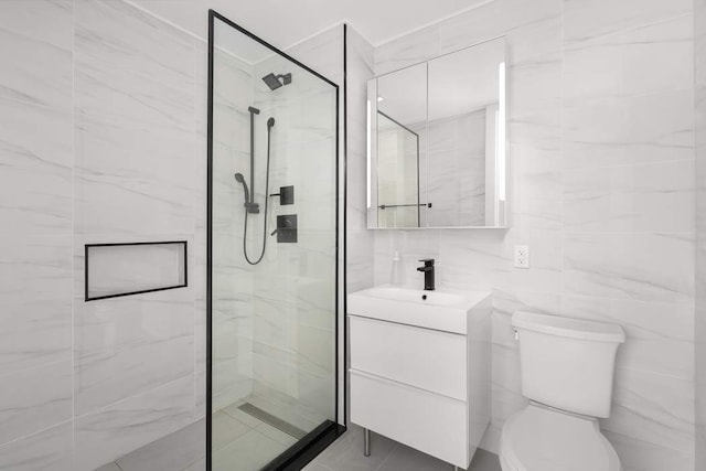 bathroom with tile walls, a stall shower, toilet, and vanity
