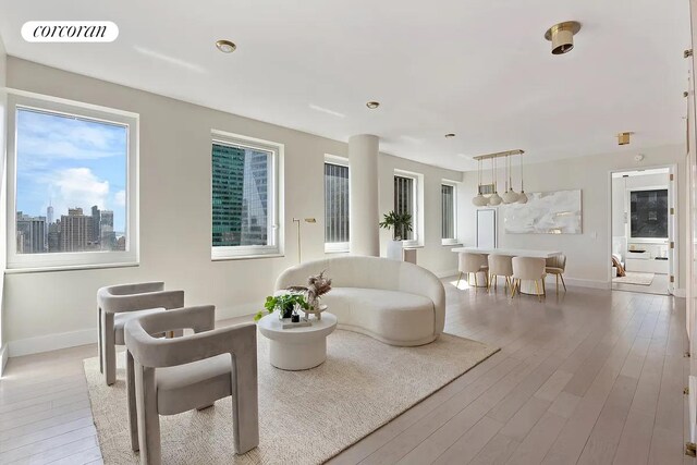 living area featuring light wood finished floors, baseboards, visible vents, and a city view