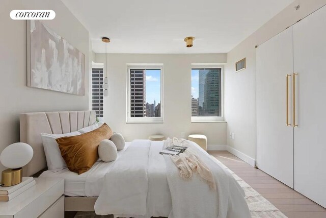 bedroom with visible vents, light wood-style flooring, and baseboards