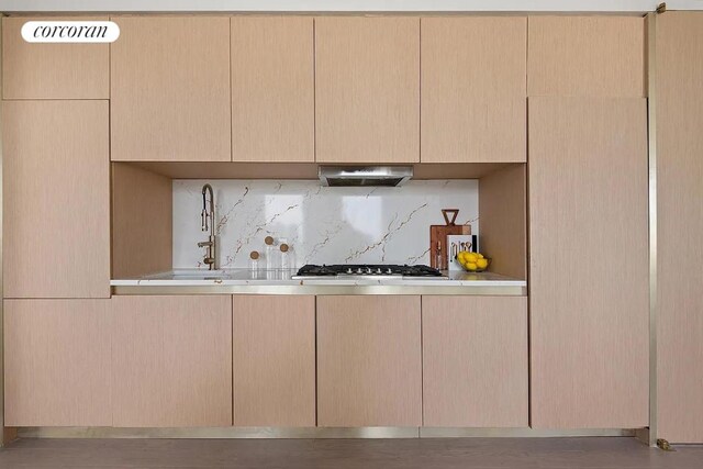 kitchen featuring light countertops, tasteful backsplash, extractor fan, and a sink