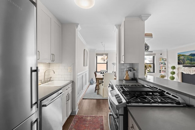 kitchen with sink, white cabinets, appliances with stainless steel finishes, and crown molding