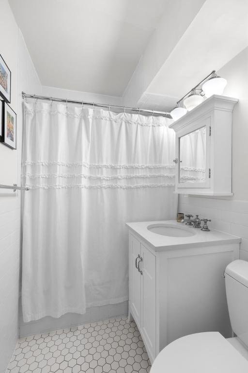 full bathroom featuring toilet, tile patterned flooring, tile walls, shower / bath combination with curtain, and vanity