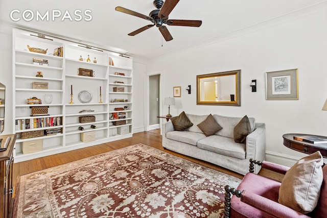 living room featuring baseboards, crown molding, a ceiling fan, and wood finished floors