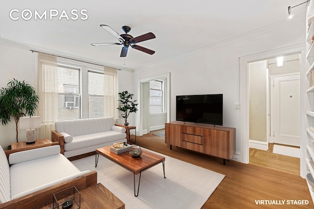 living room with baseboards, ornamental molding, light wood-style flooring, and a ceiling fan