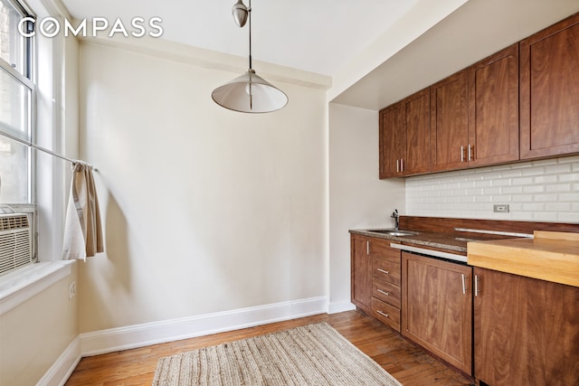 kitchen with light wood-style floors, tasteful backsplash, baseboards, and a sink