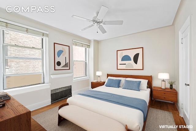 bedroom with ceiling fan, wood finished floors, and baseboards