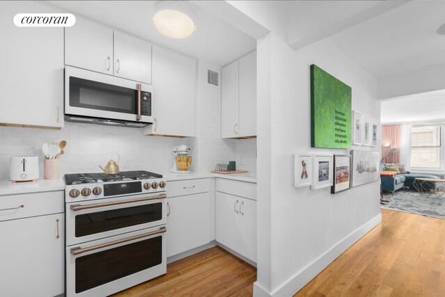 kitchen featuring double oven range, white cabinets, and decorative backsplash