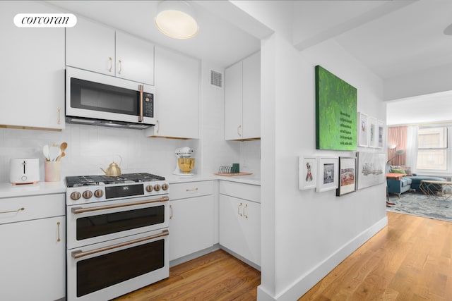 kitchen with light wood-type flooring, light countertops, visible vents, and white appliances