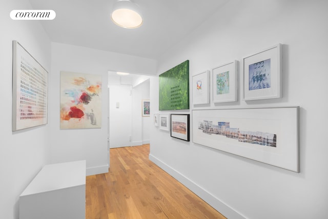 corridor featuring baseboards, visible vents, and light wood-type flooring
