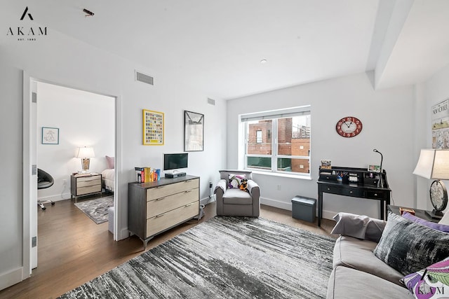 living area with wood finished floors, visible vents, and baseboards