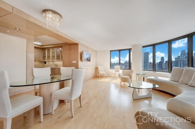 dining space featuring light wood-type flooring, a city view, and an inviting chandelier