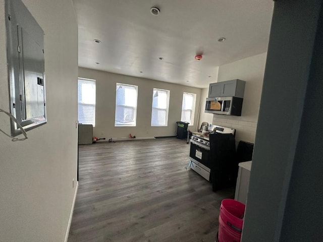 kitchen featuring gray cabinetry, open floor plan, light countertops, stainless steel microwave, and range with gas cooktop