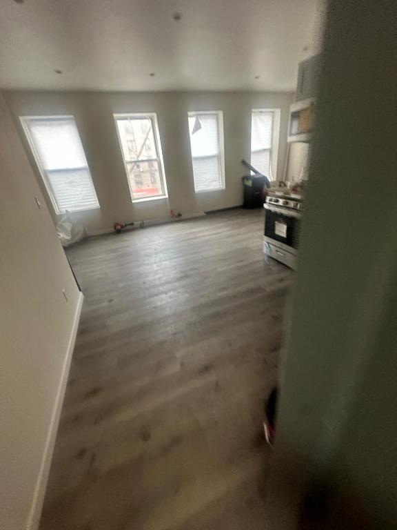 unfurnished living room featuring wood finished floors and baseboards