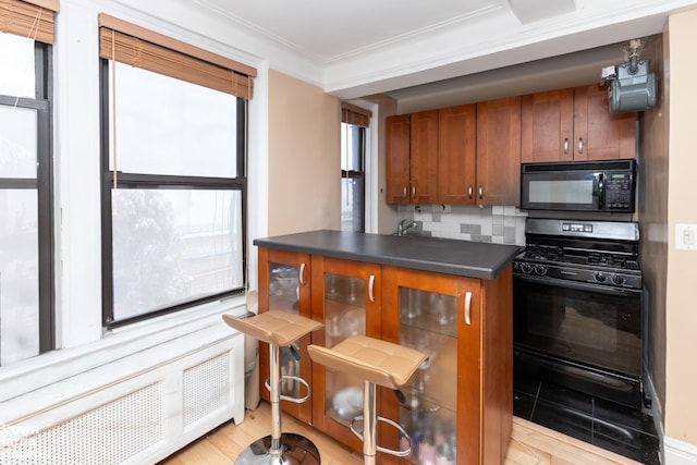 kitchen with backsplash, ornamental molding, and black appliances