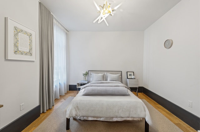 bedroom with a chandelier, wood finished floors, and baseboards